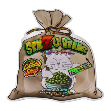A die-cut sticker or decal shaped like a brown paper sack filled with green cannabis flower. The front features a cartoon white cat holding a bowl of green beans/peas, large stylized text reading 'SENZU BEANS,' smaller text including 'The Candy Shop,' and 'FIRE NINJA UP.